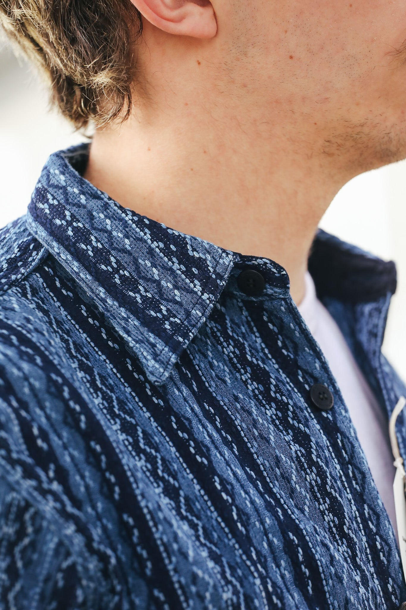 Close-up of a person wearing a blue textured shirt with a blurred background