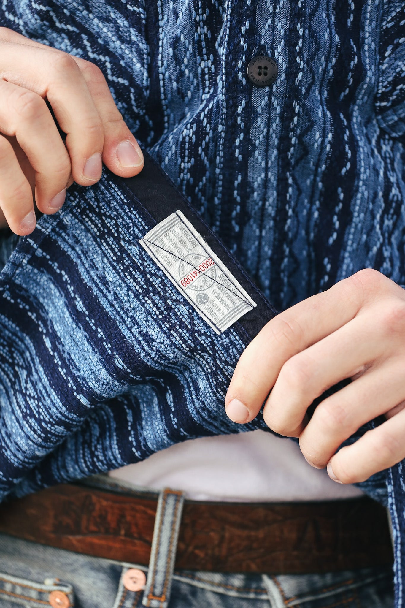 Close-up of a person adjusting a belt with a visible brand label.