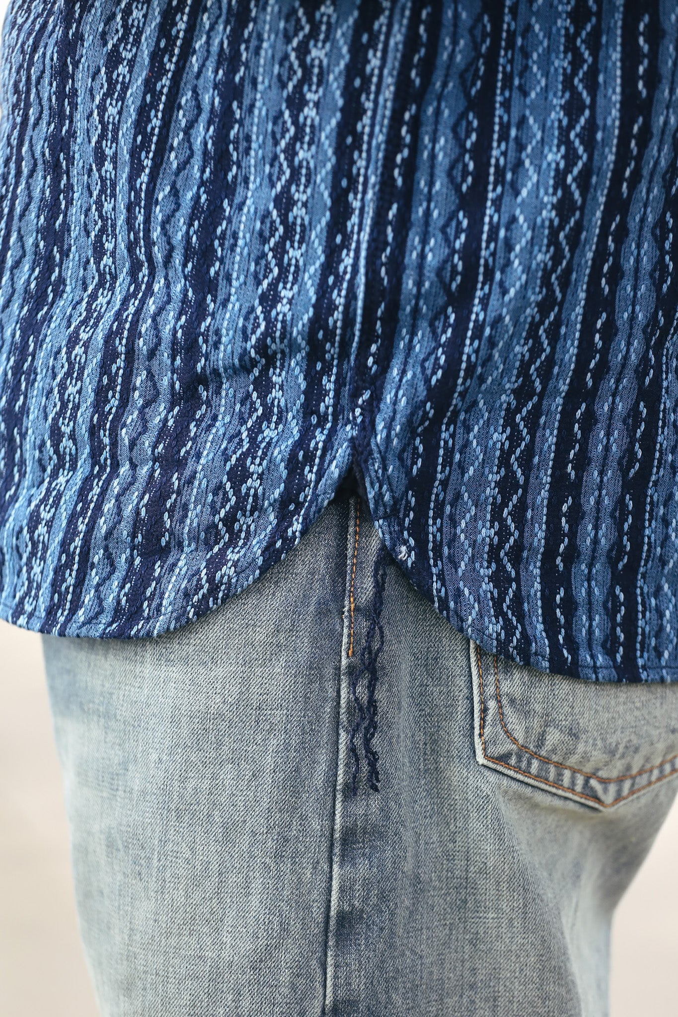 Close-up of a person wearing a blue patterned shirt and jeans.