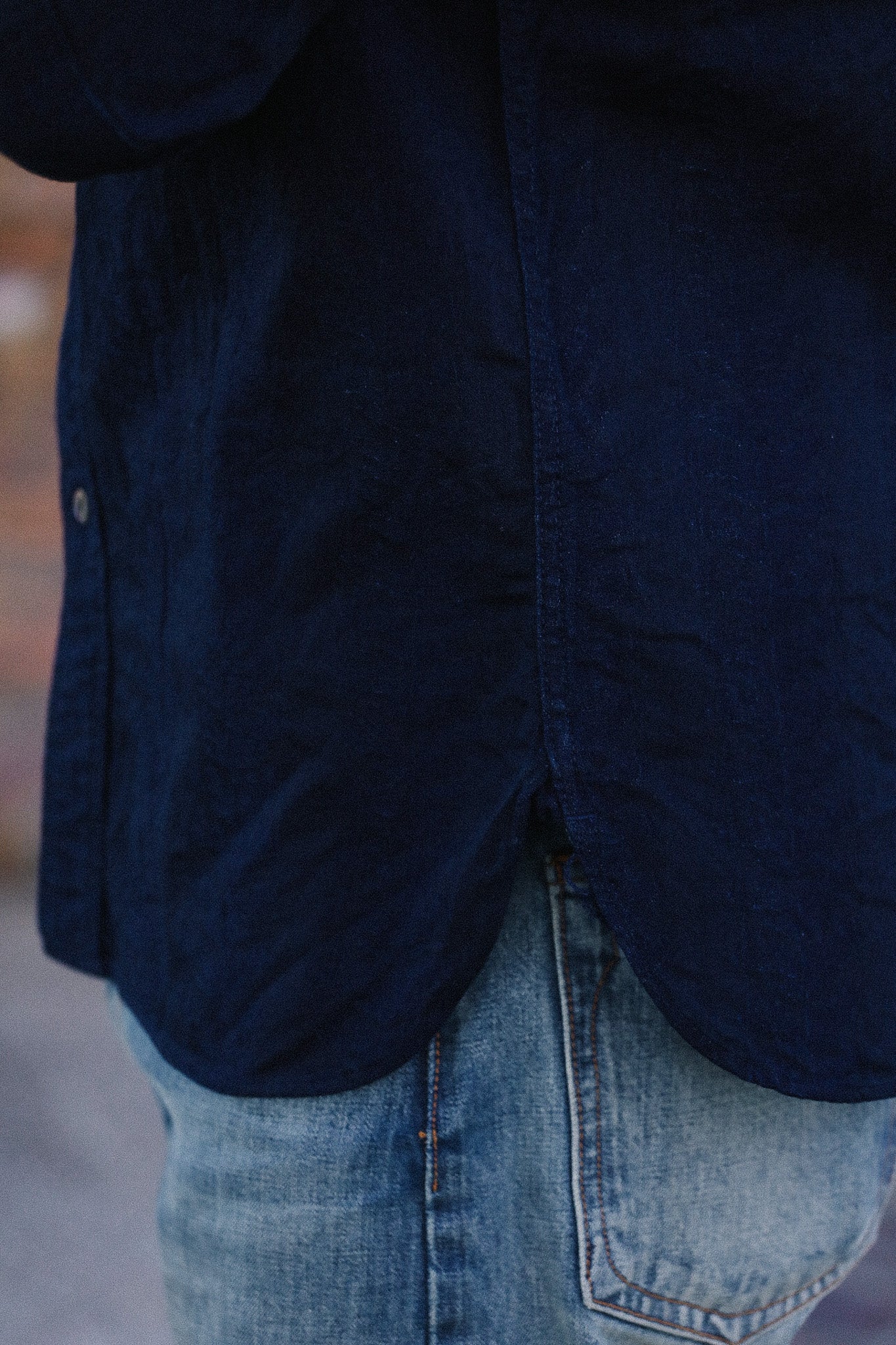 Navy jacket and blue jeans worn by a person, with a blurred background