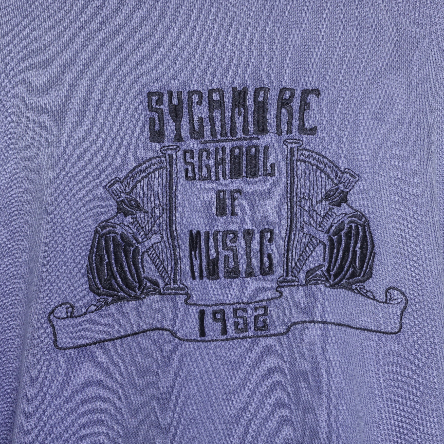 Close-up of purple fabric with black embroidered Sycamore School of Music 1952 logo featuring two harp players