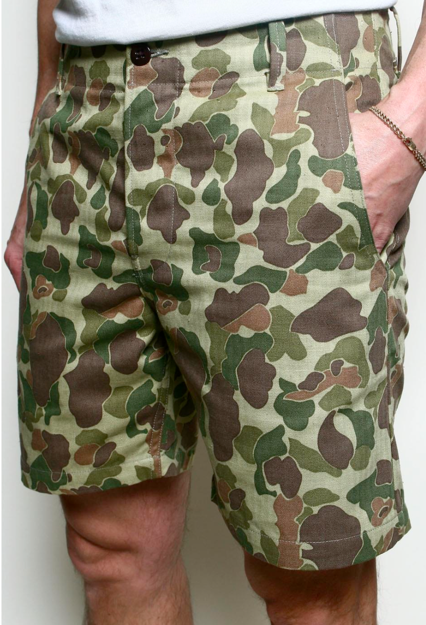 Camouflage shorts worn by a person on a plain background