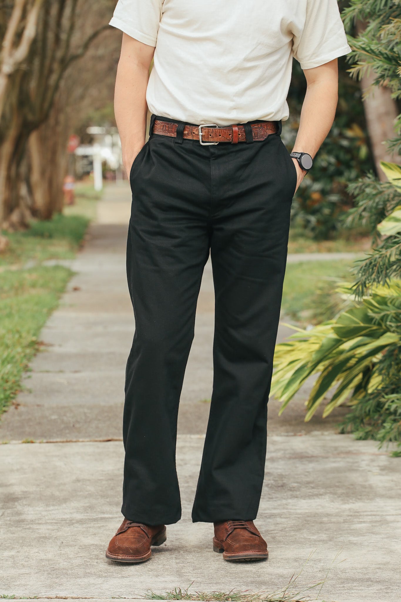 Person wearing black pants and a white shirt outdoors on a wooden path.