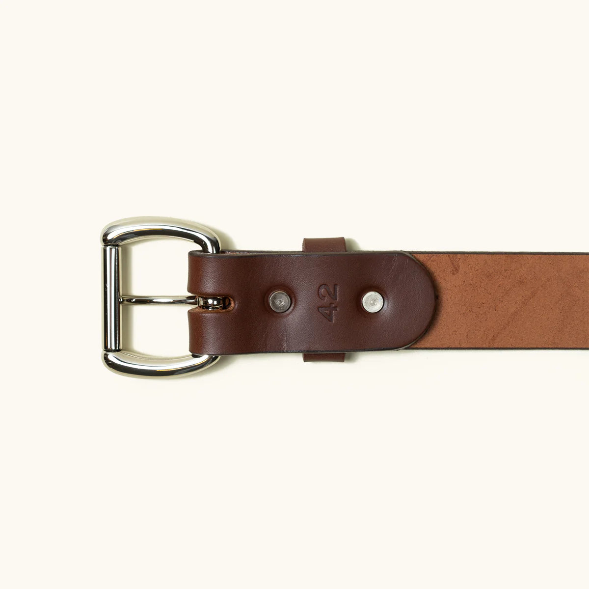 Close-up of a cognac leather belt with silver buckle and size 42 embossed, displayed on a light background