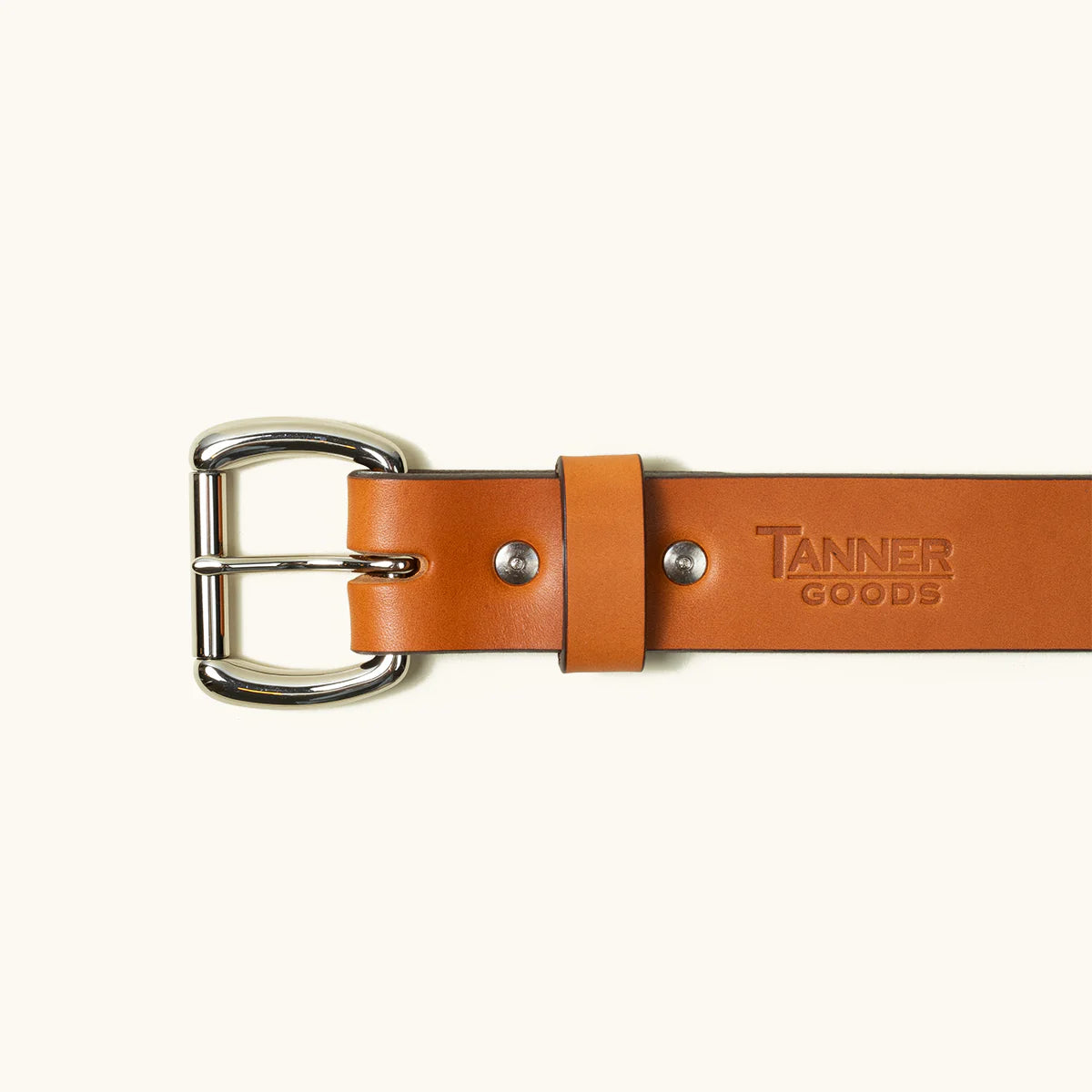 Close-up of Tanner Goods saddle leather belt with silver buckle on light background