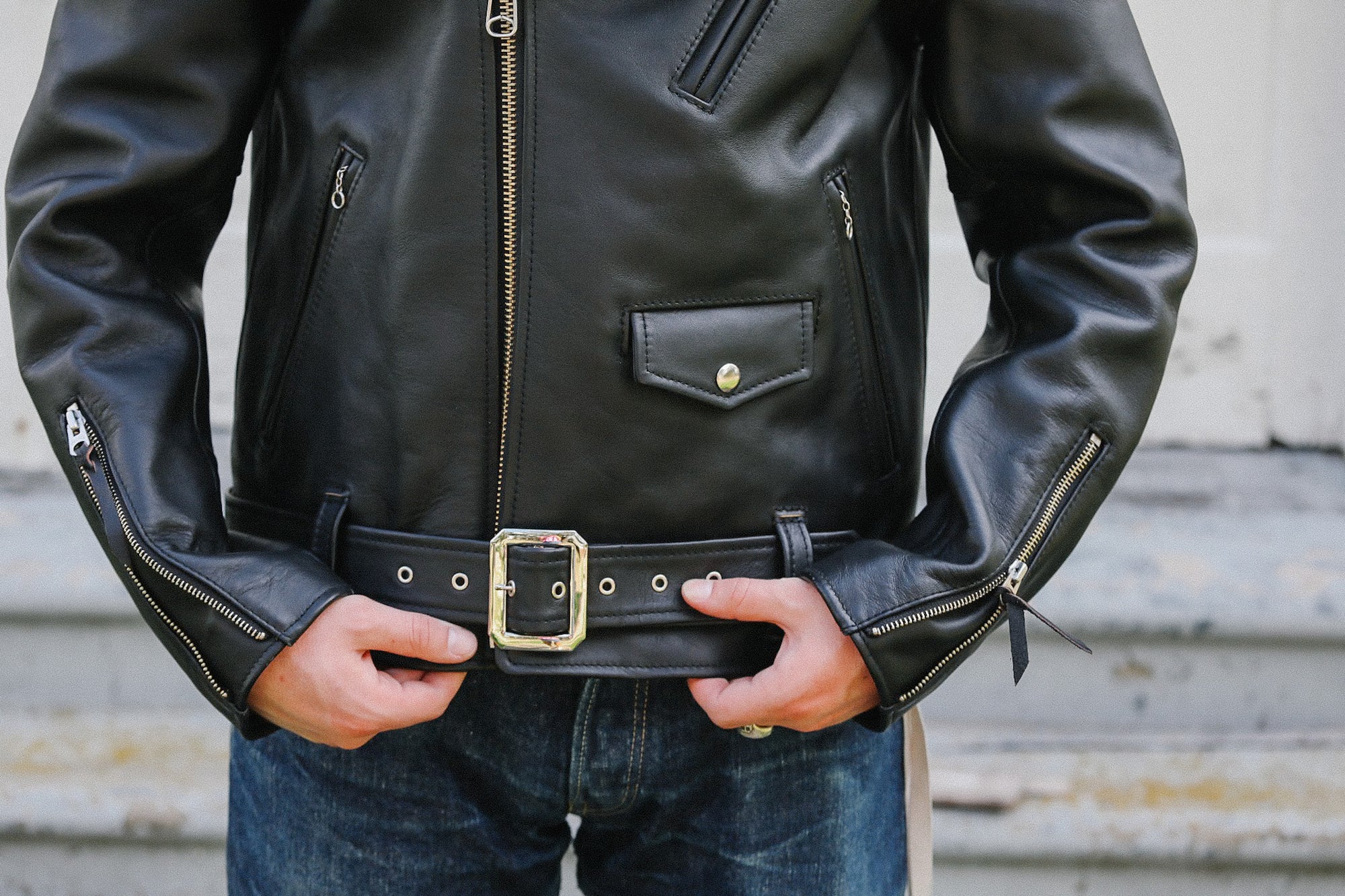 Close-up of black sumi dyed double riders leather jacket with silver zippers and belt buckle