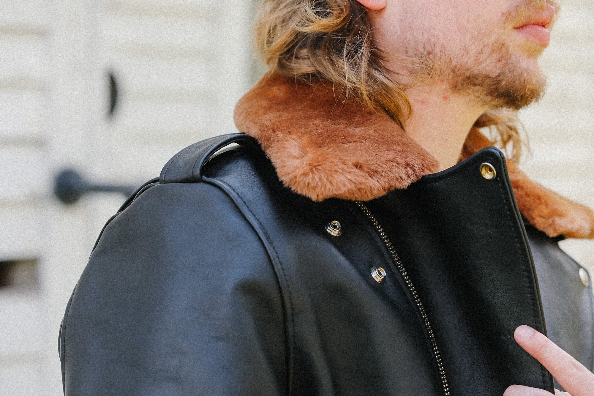 Close-up of man wearing black horsehide leather jacket with saddle dyed brown fur collar and metal snaps