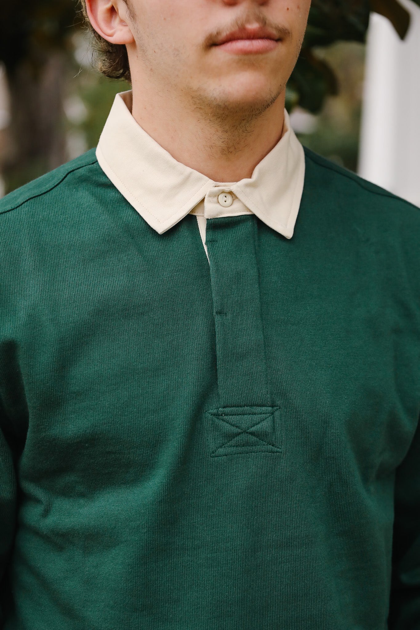 Green polo shirt with a white collar worn by a person, blurred background