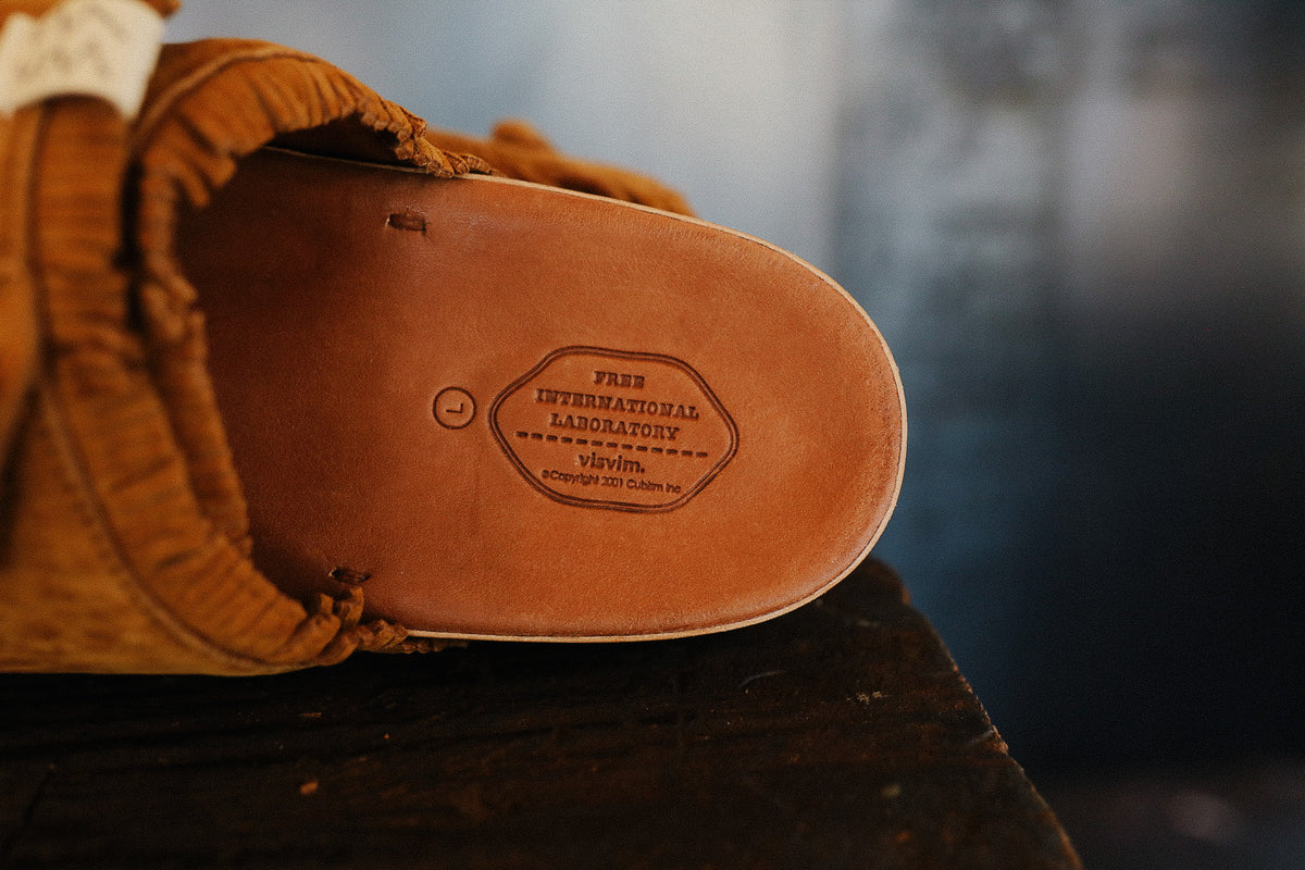 Close-up of a brown leather shoe sole with a brand label on a blurred background