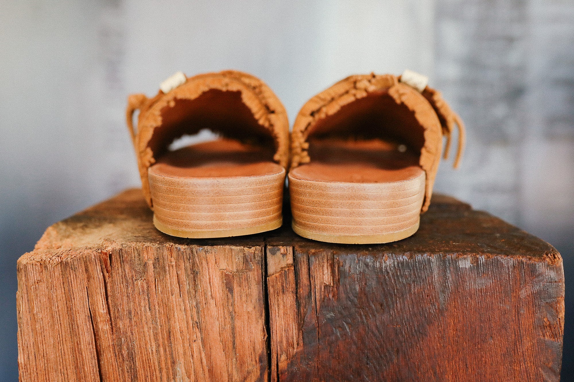 Pair of brown sandals on a wooden block with a blurred background