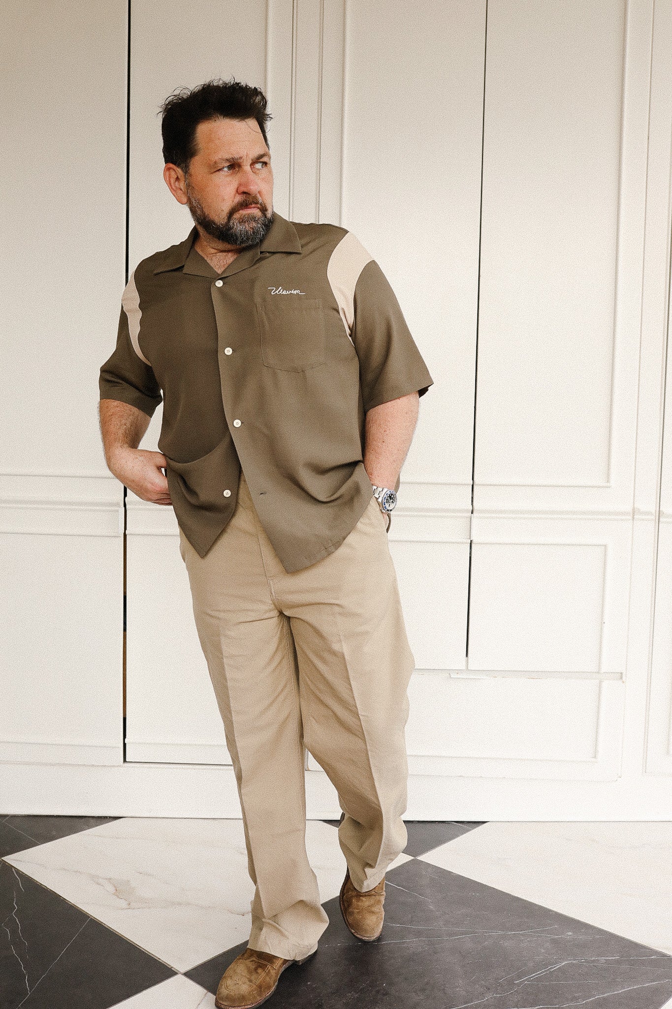 Man wearing a brown shirt with 'Johnstons' branding in a room with white walls and a checkered floor.
