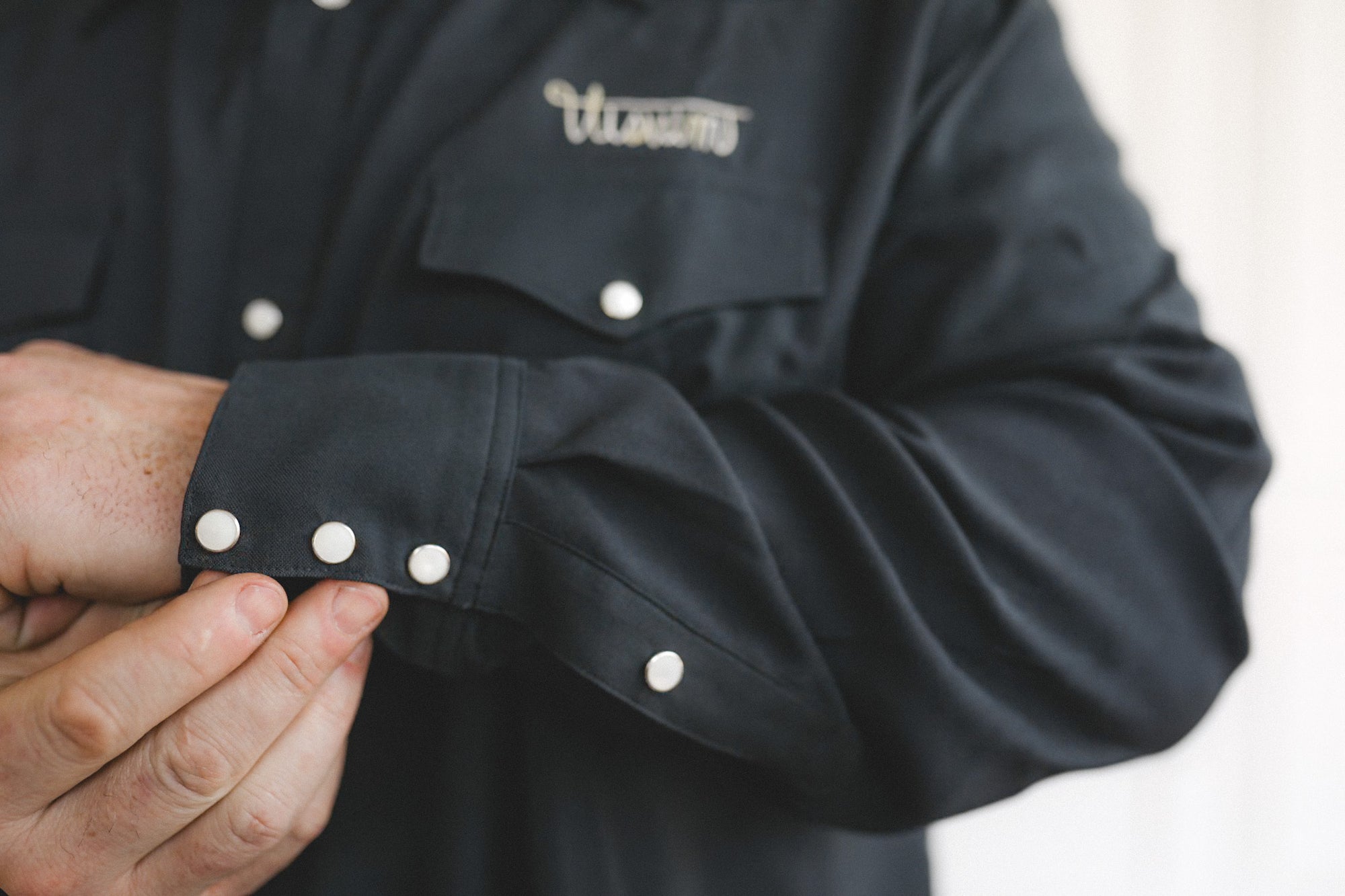 Close-up of a black chef's coat with white buttons on a blurred background