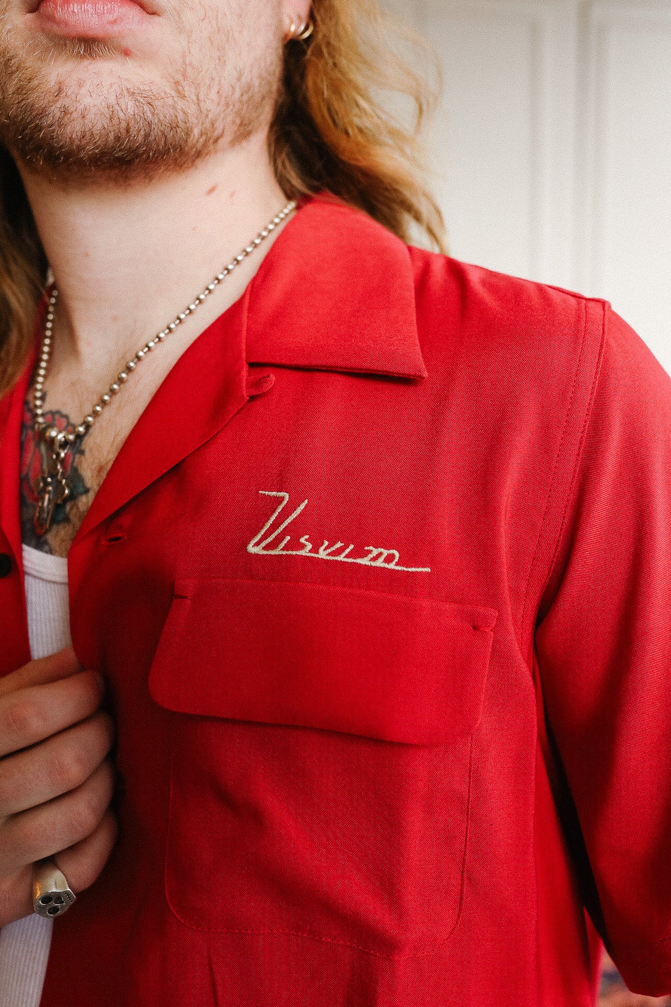 Person wearing a red shirt with 'Virum' logo, holding a white cup.