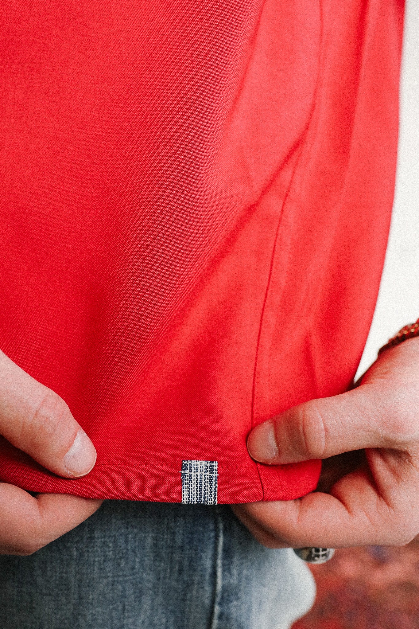 Close-up of a red jacket with a brand label being held by hands.