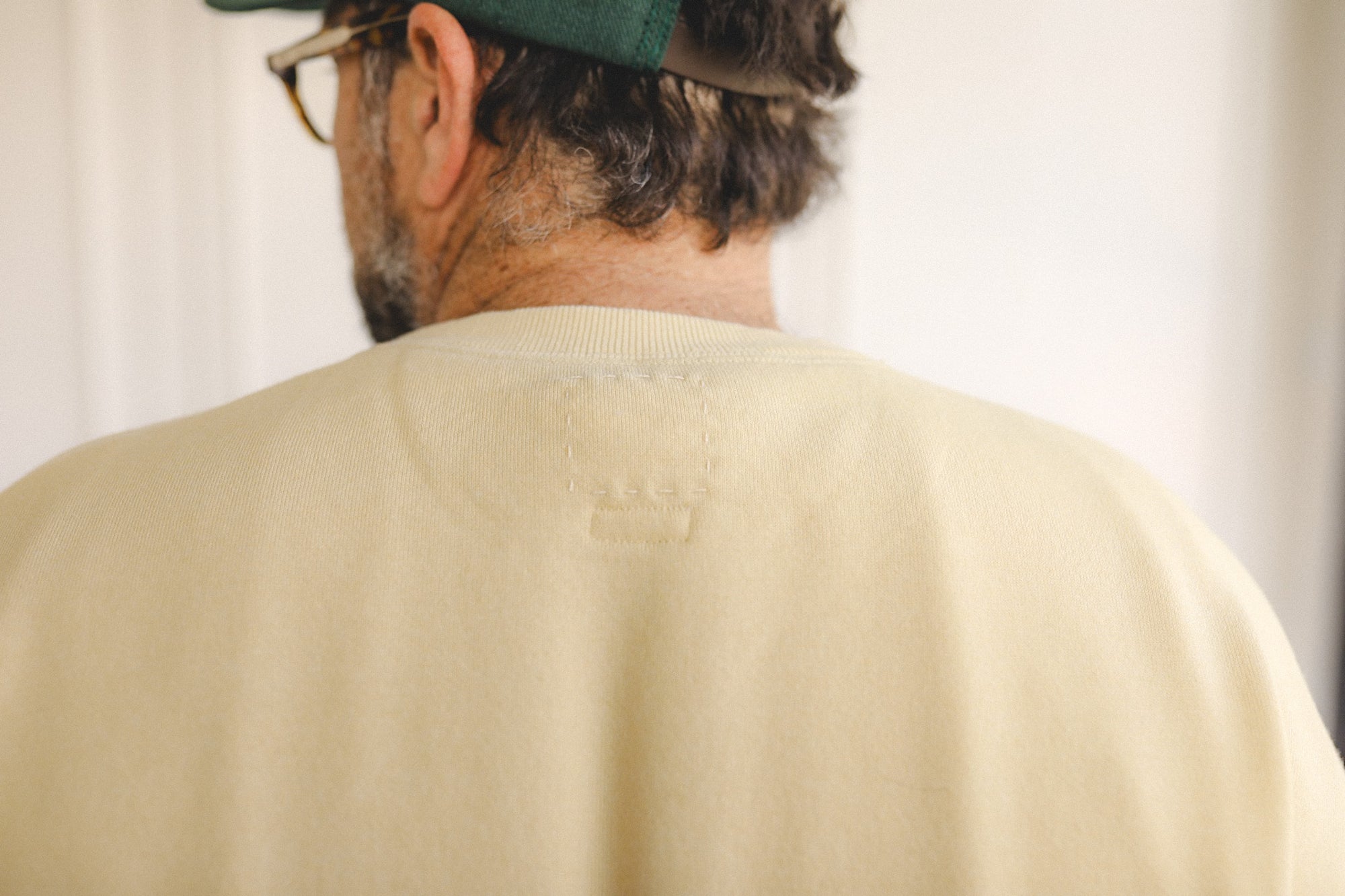 Person wearing a beige sweater with a visible brand logo on the back.