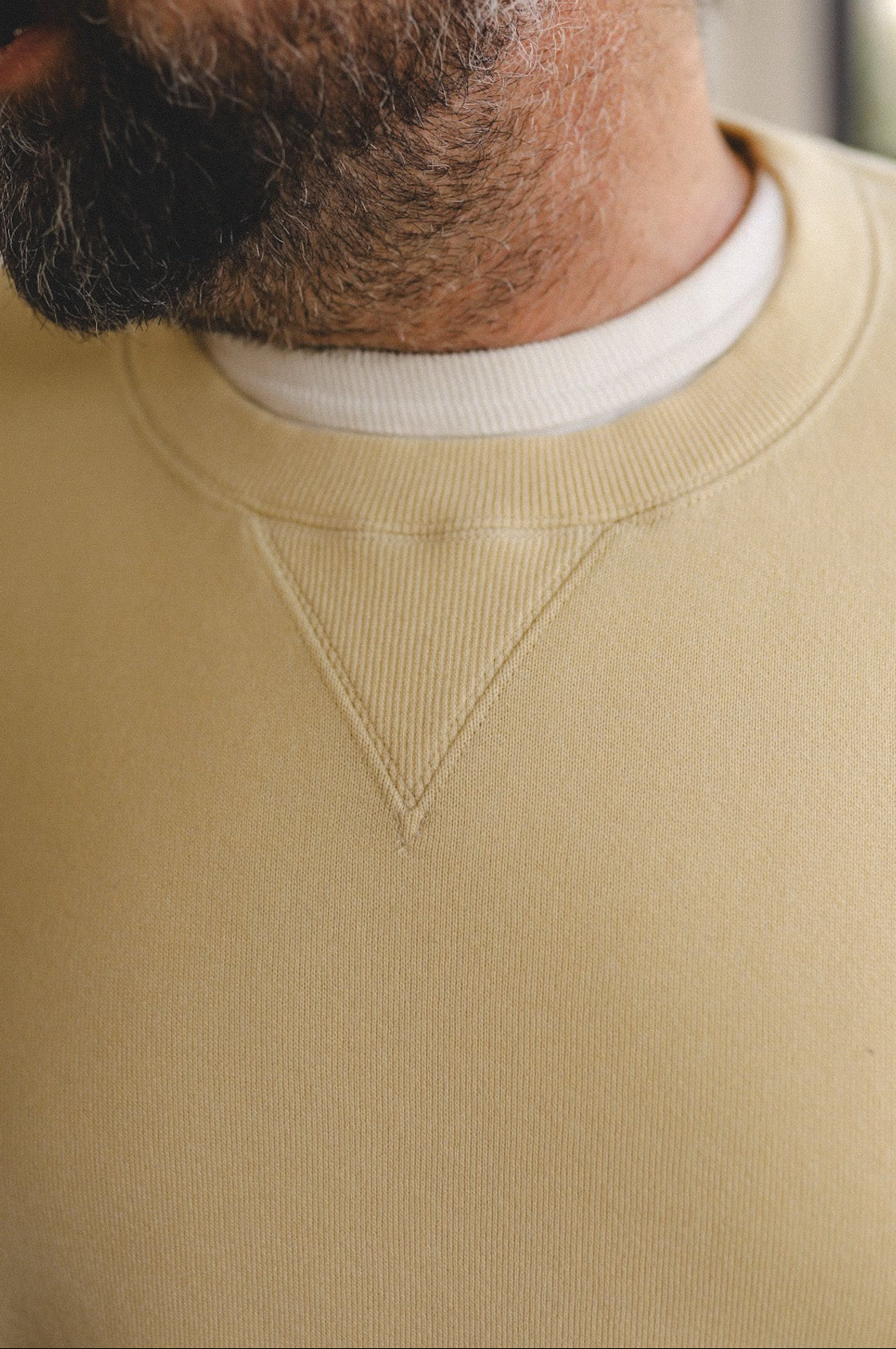 Close-up of a person wearing a beige sweater with a white collar.