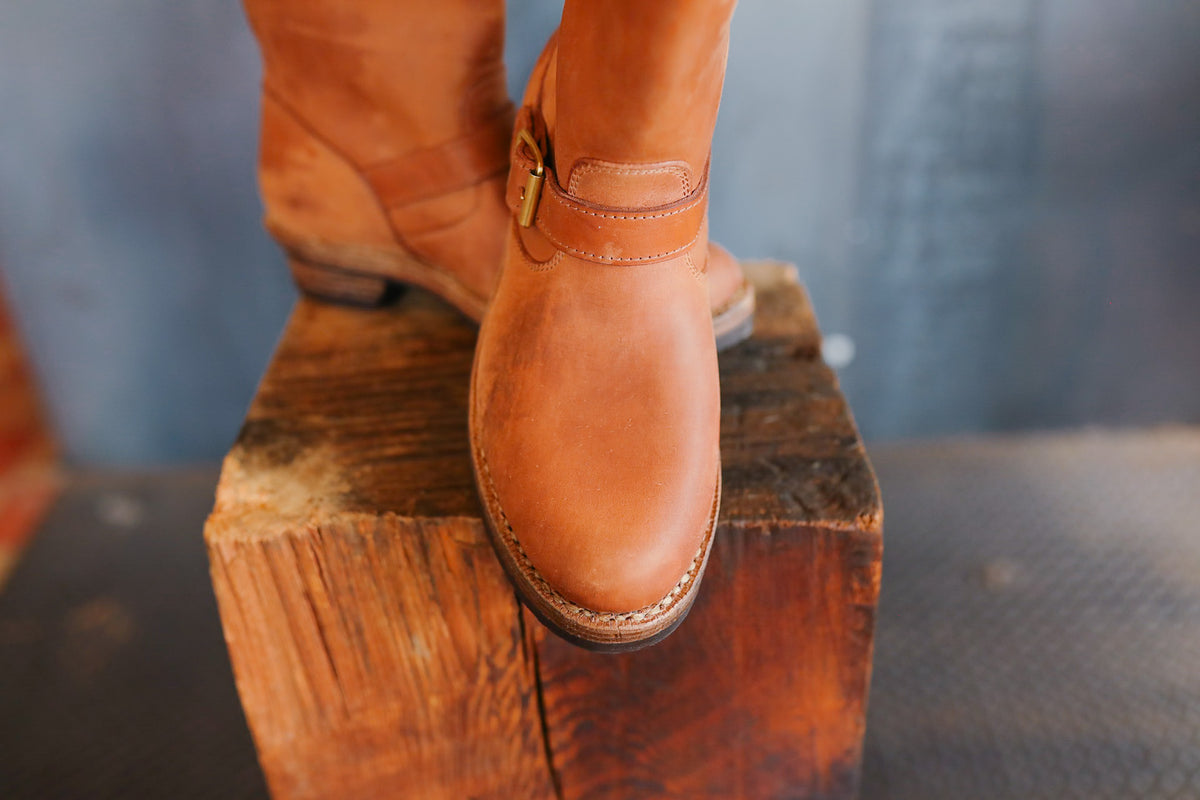 Brown leather boot on a wooden block with a blurred background