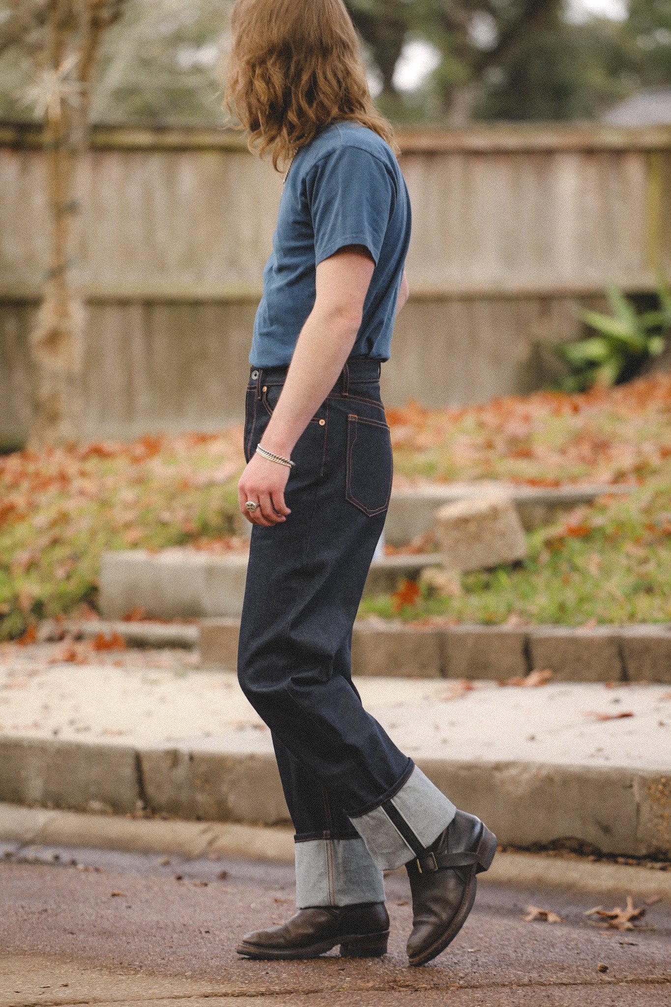 Person wearing wide straight 16.5oz Kaisen Indigo denim jeans with cuffed hems and black boots outdoors