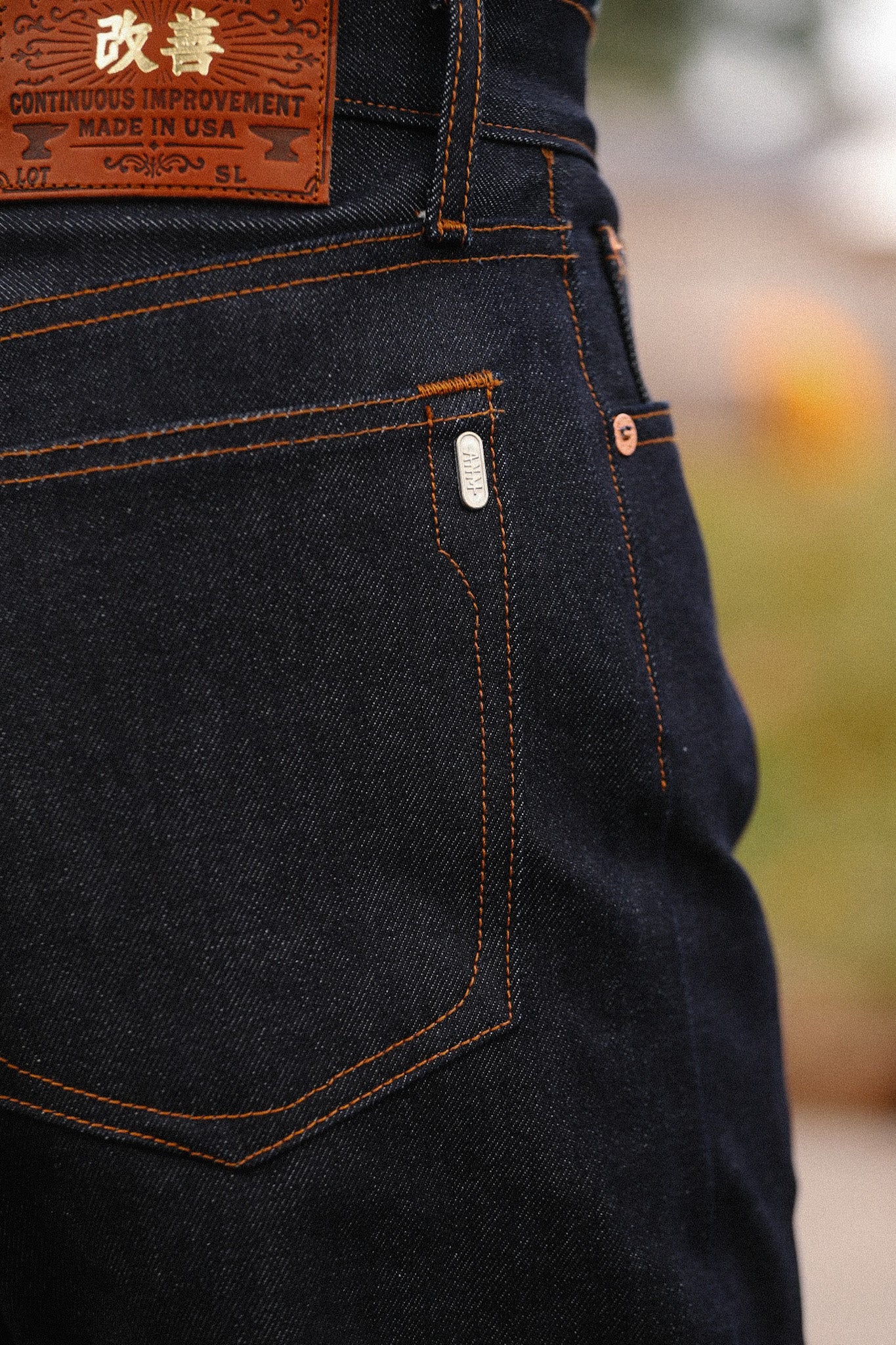 Close-up of Iron Shop Provisions dark indigo denim jeans with orange stitching and leather patch on back pocket