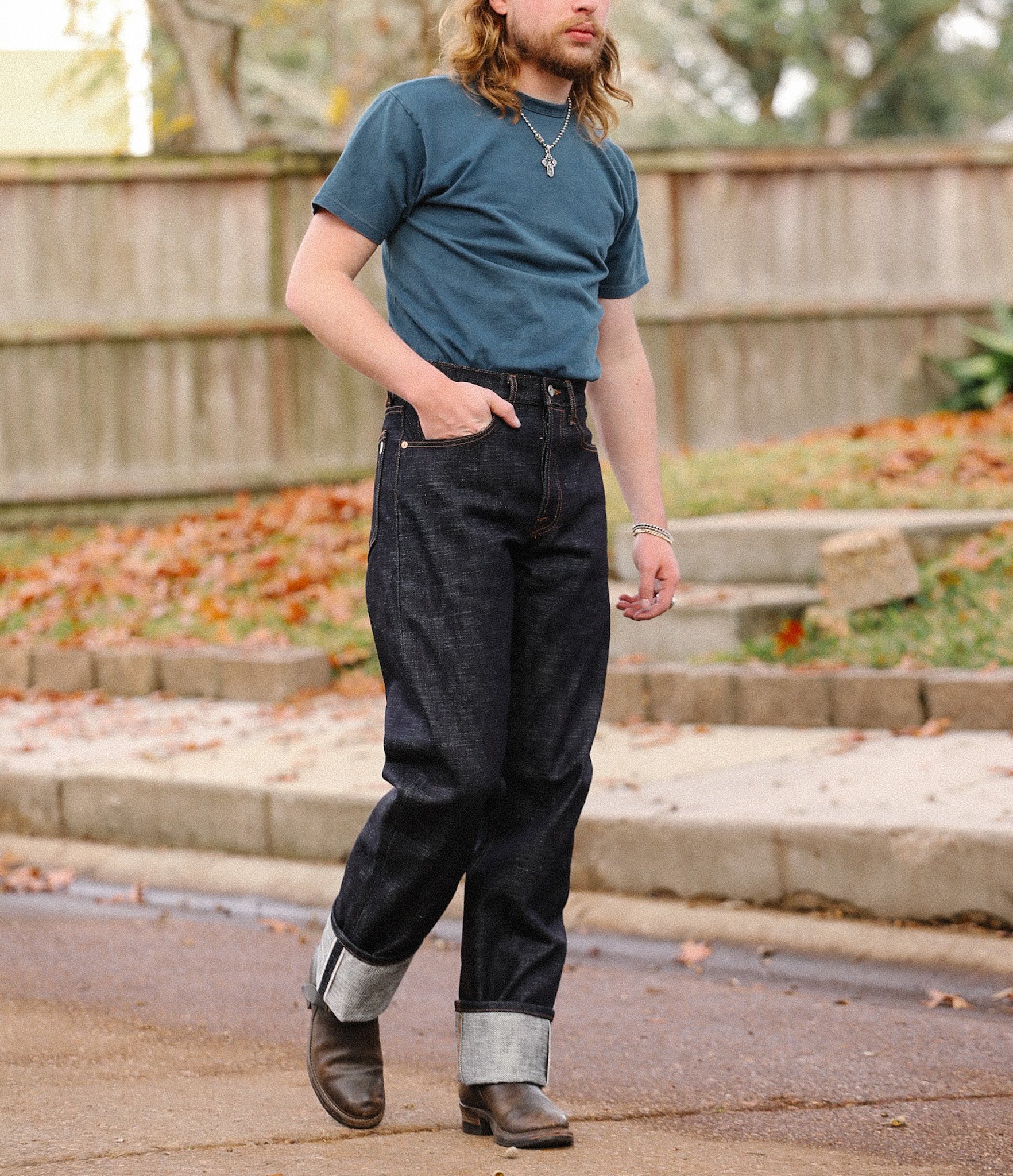 Man wearing Iron Shop Provisions 20oz double slub indigo wide straight jeans with cuffs, blue t-shirt, and brown boots outdoors