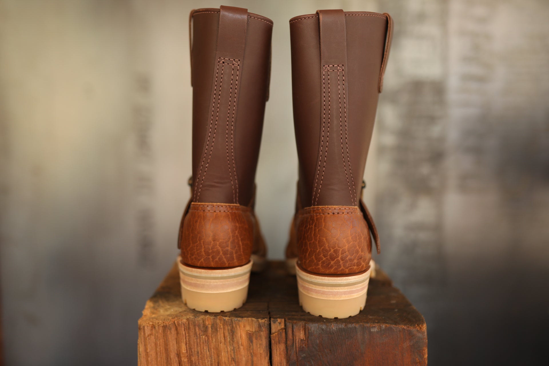 Pair of brown leather Wesco ISP Boss Engineer boots on wooden block with textured heel