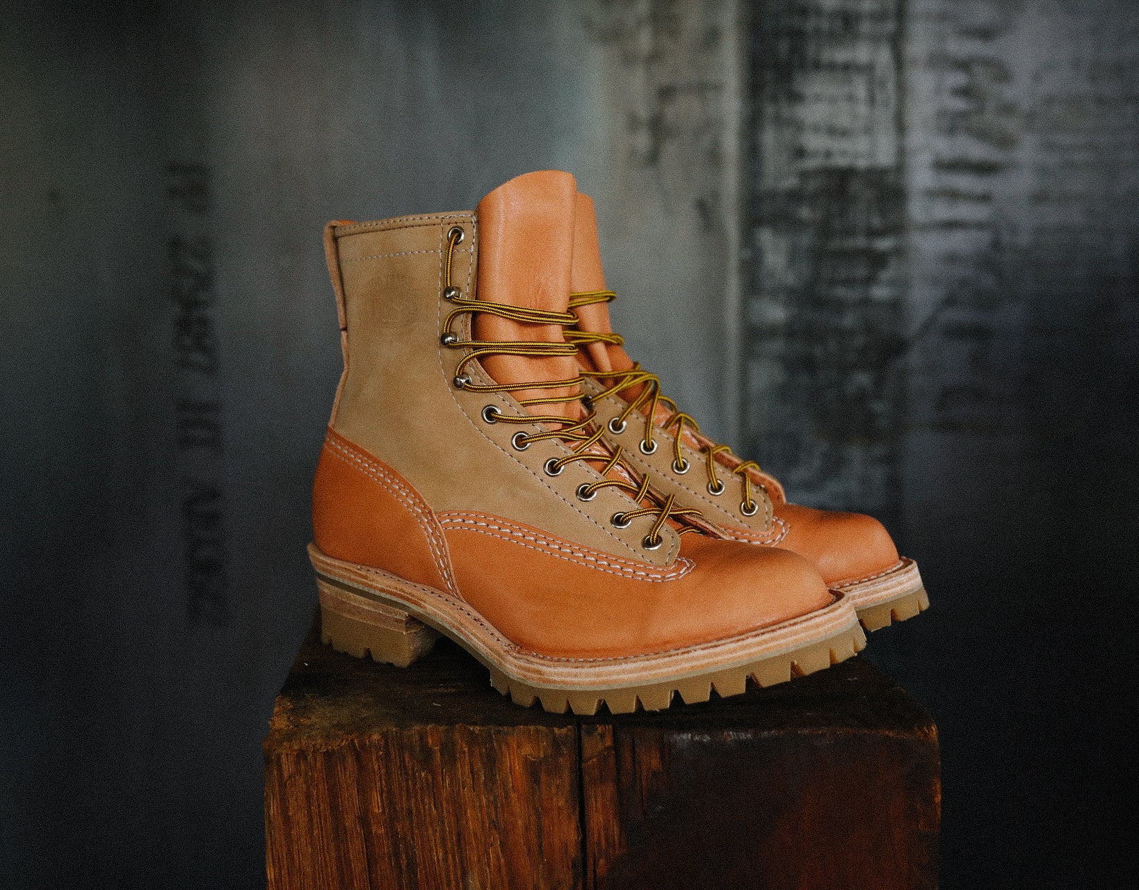 Pair of tan and brown leather work boots with yellow laces on wooden surface