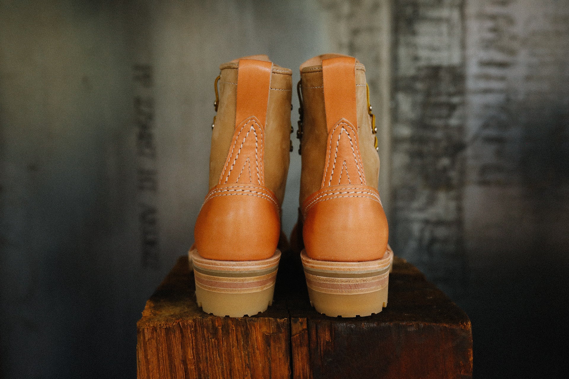 Pair of natural burlap and leather Wesco Jobmaster boots on wooden block with industrial background