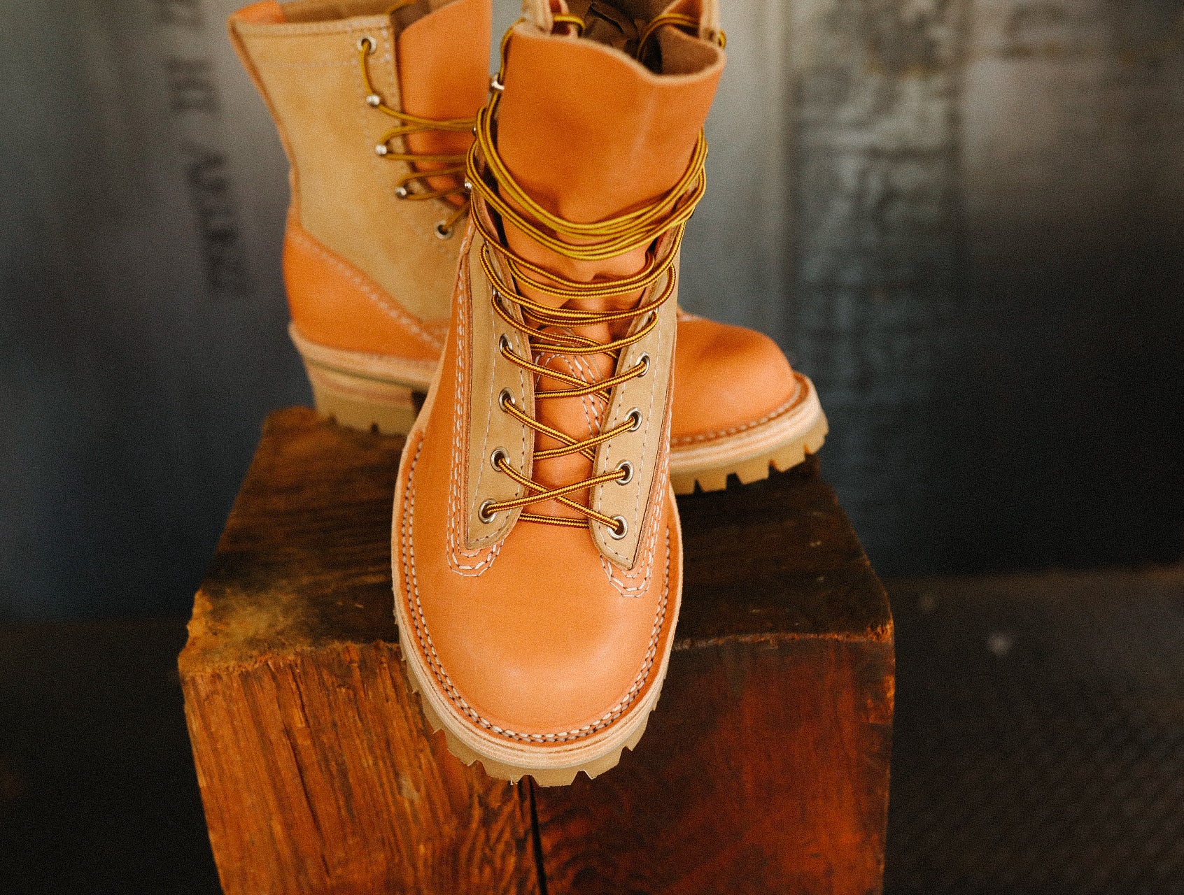Pair of natural burlap and leather work boots with durable laces on rustic wooden block