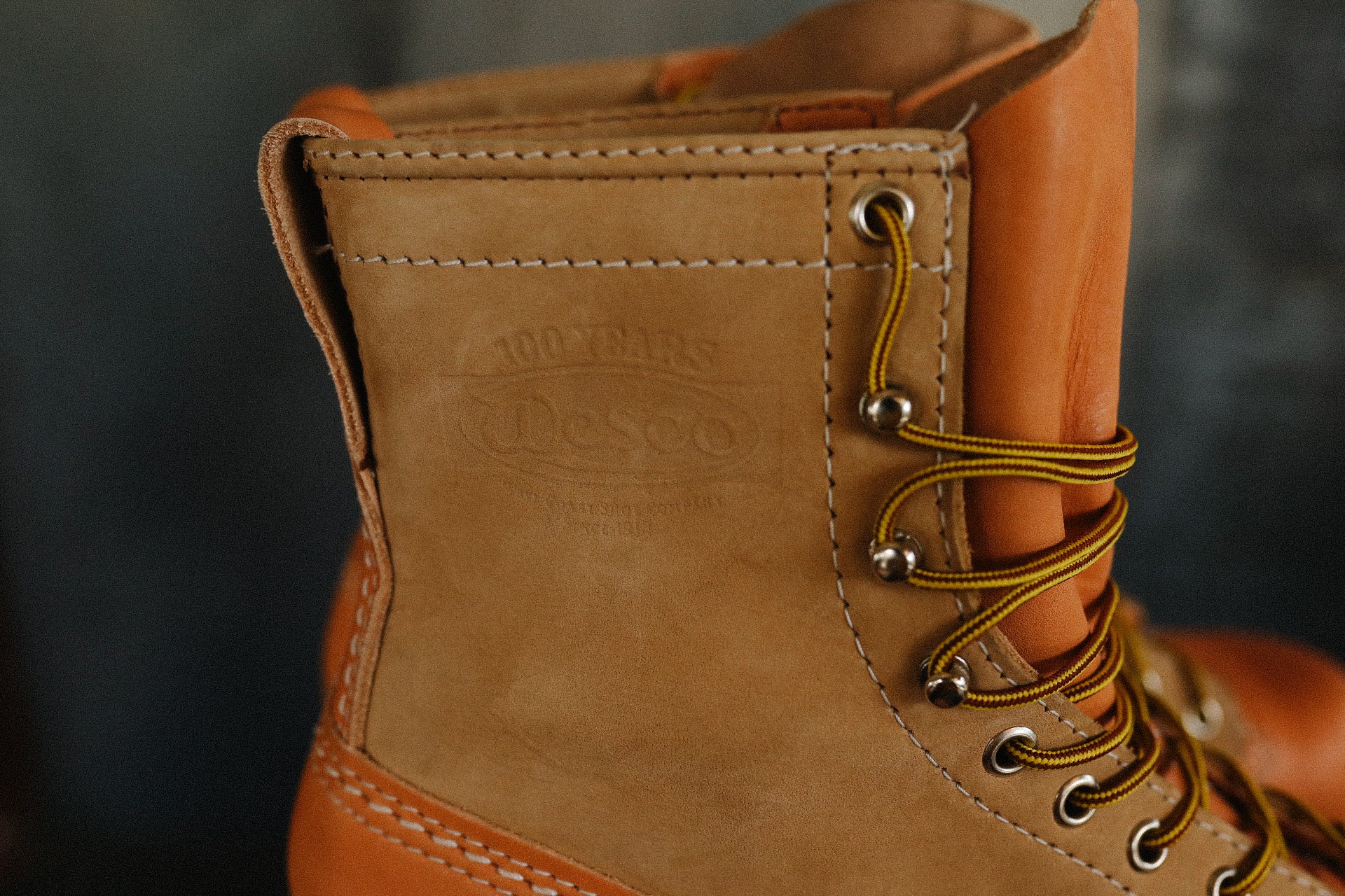 Close-up of tan Wesco leather work boot with yellow and brown laces and detailed stitching