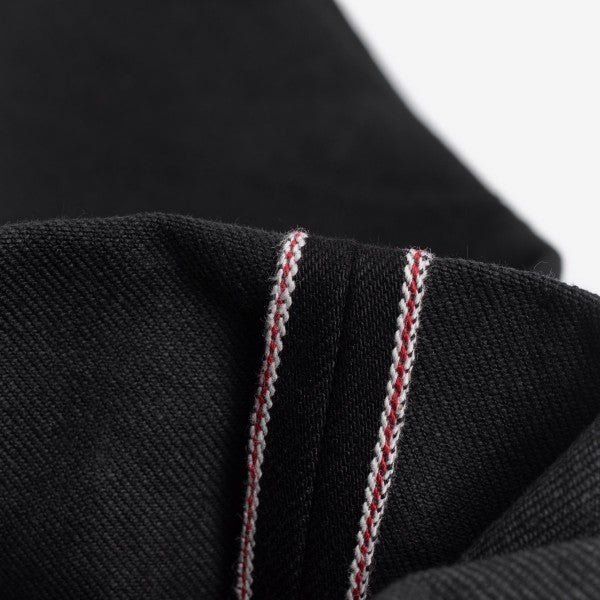 Close-up of black denim fabric with red and white selvedge stitching detail from Iron Shop Provisions