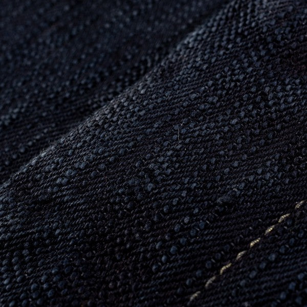 Close-up of textured dark denim fabric with detailed weaving and stitching