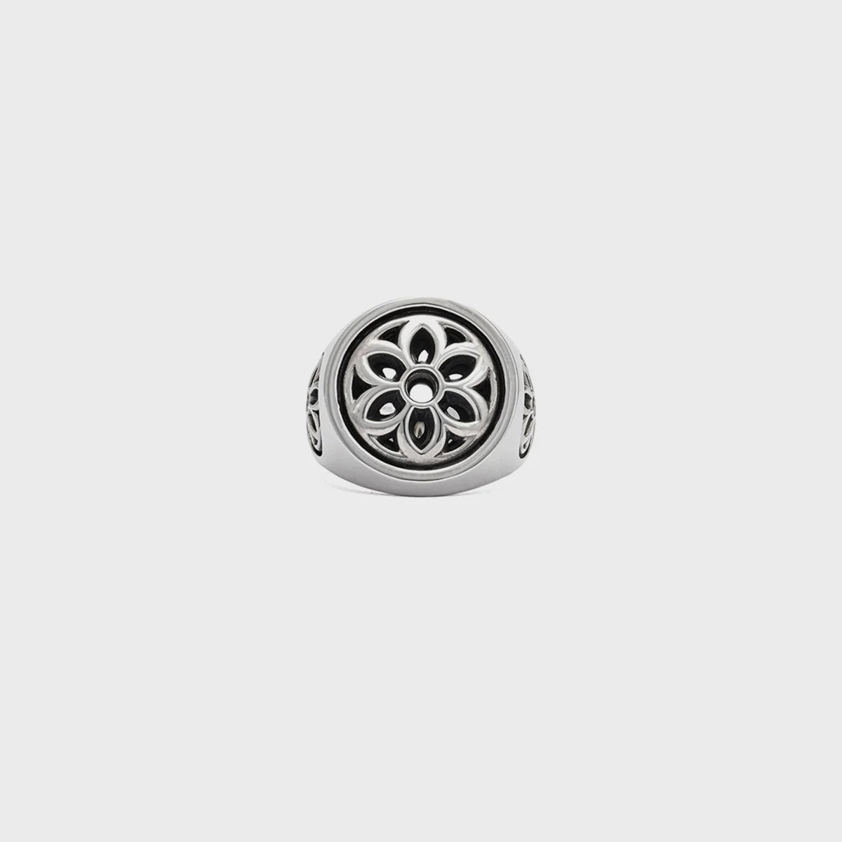 Silver ring with intricate floral cutout design on front and sides, minimalist background