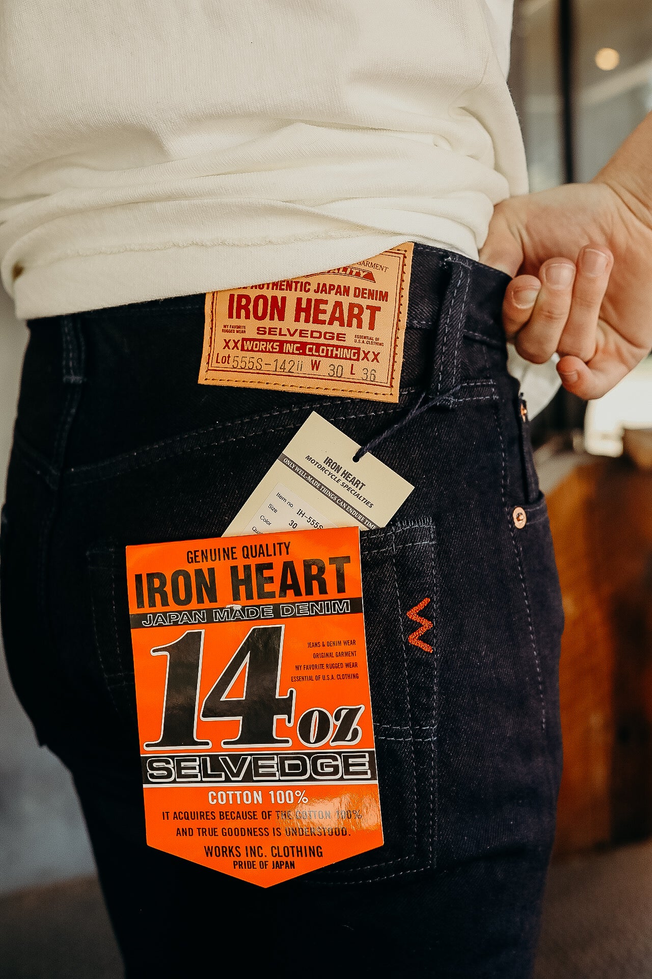 Close-up of a person wearing Iron Heart 14 oz Japanese selvedge denim jeans with authentic branding tags
