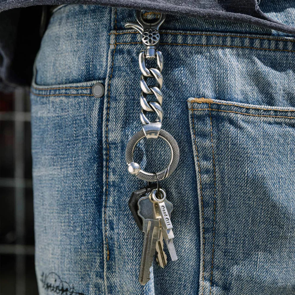 Silver keychain with keys attached to blue denim jeans pocket, featuring a thick chain link design