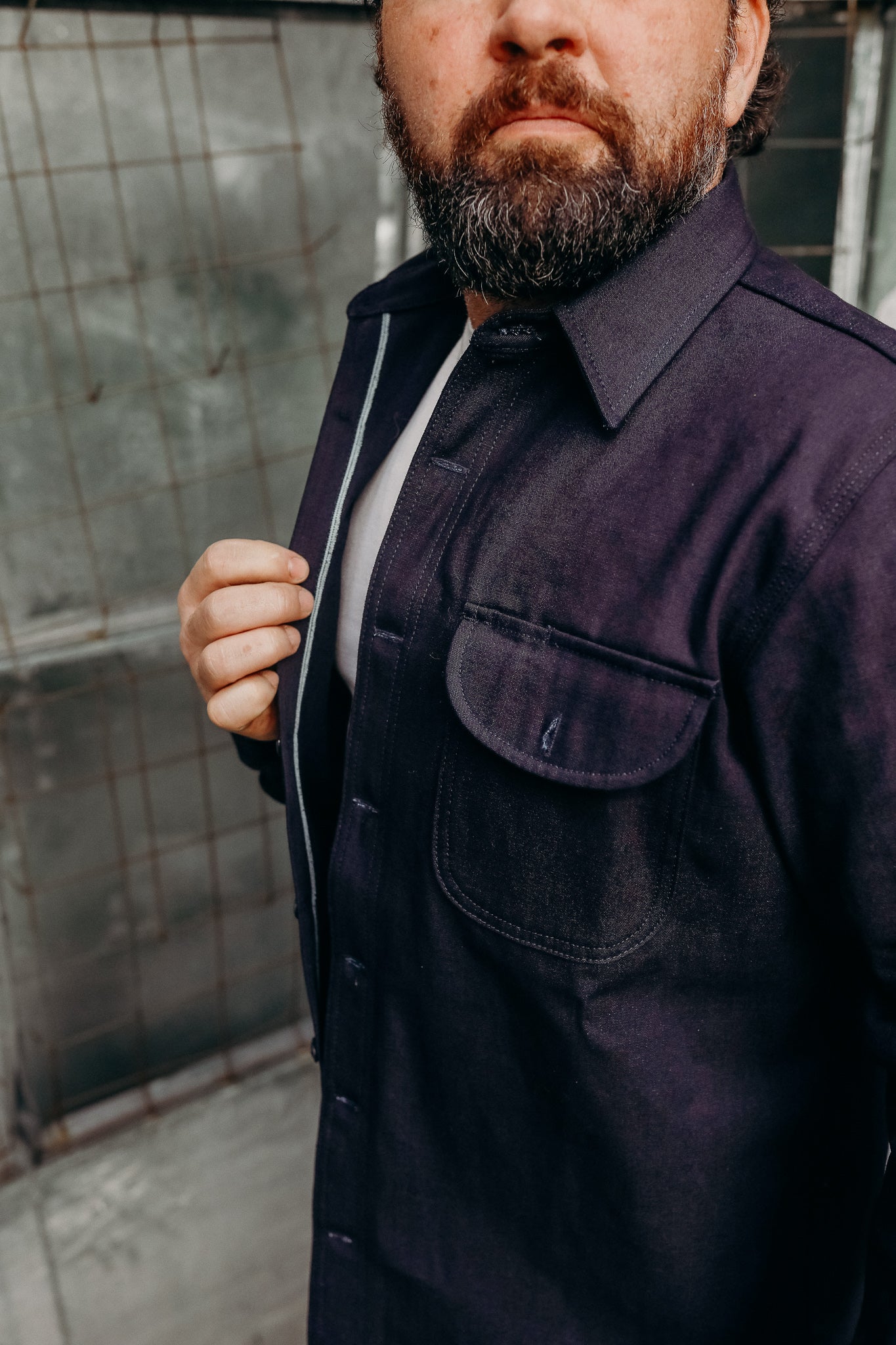 Man wearing a dark indigo work shirt jacket from Iron Shop Provisions with a front flap pocket detail