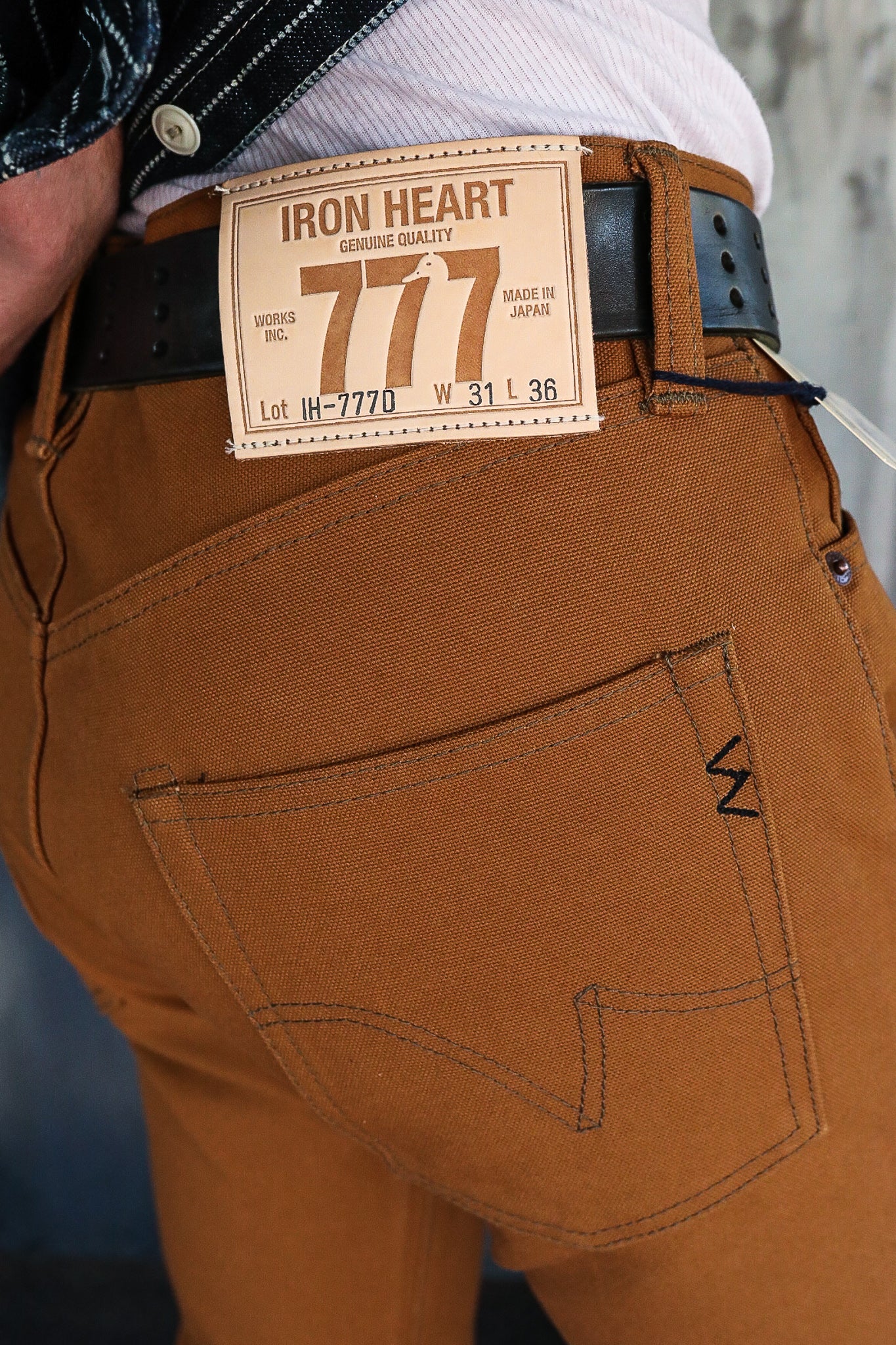 Close-up of brown Iron Heart jeans back pocket with leather patch label and black belt