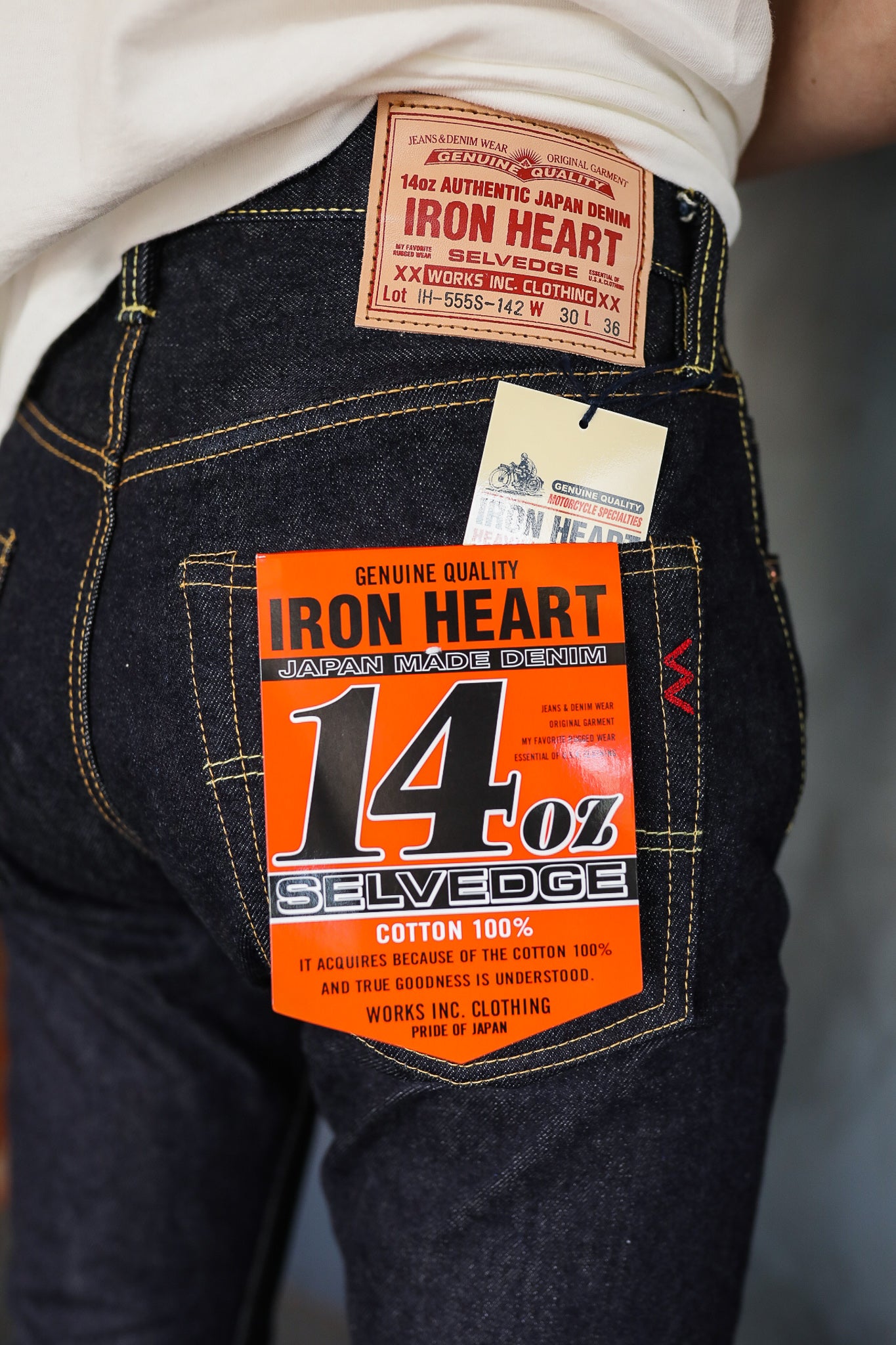 Close-up of dark blue Iron Heart 14oz selvedge Japanese denim jeans with orange label on back pocket