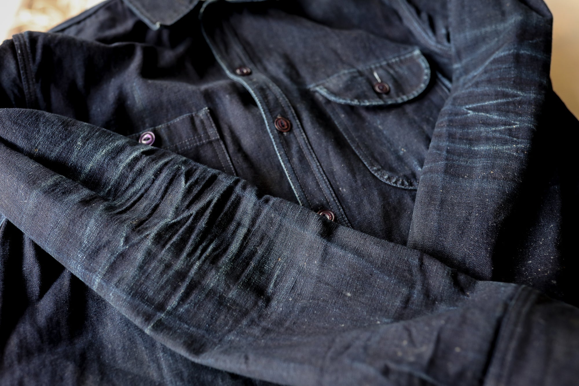 Close-up of dark indigo denim shirt with visible wear creases and buttoned chest pockets from Iron Shop Provisions