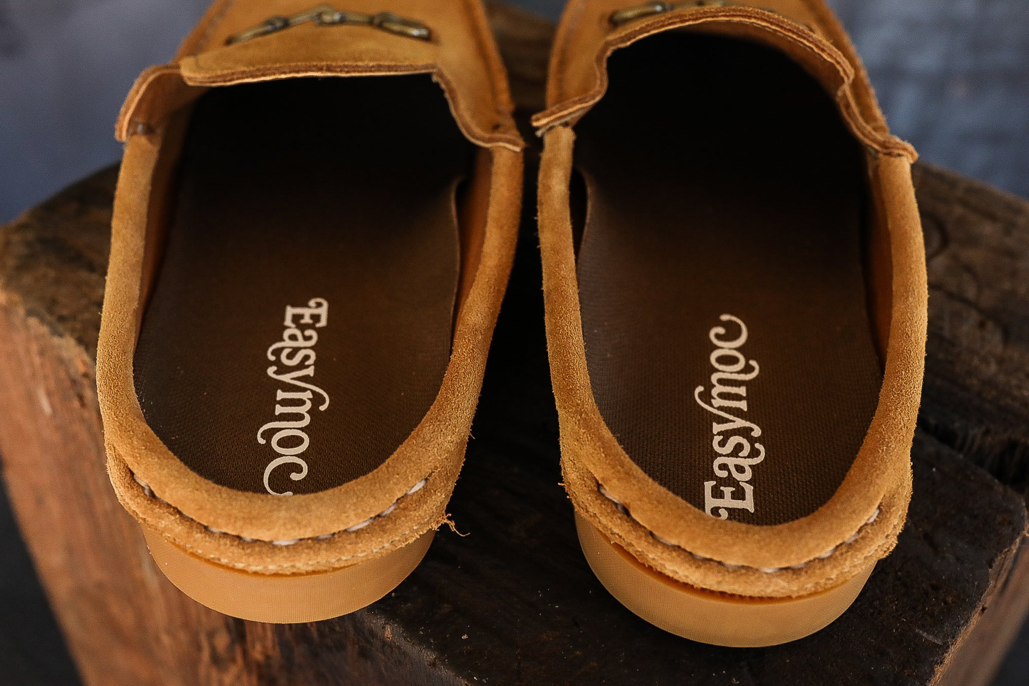 Brown suede Easy Moc slip-on shoes on rustic wooden surface