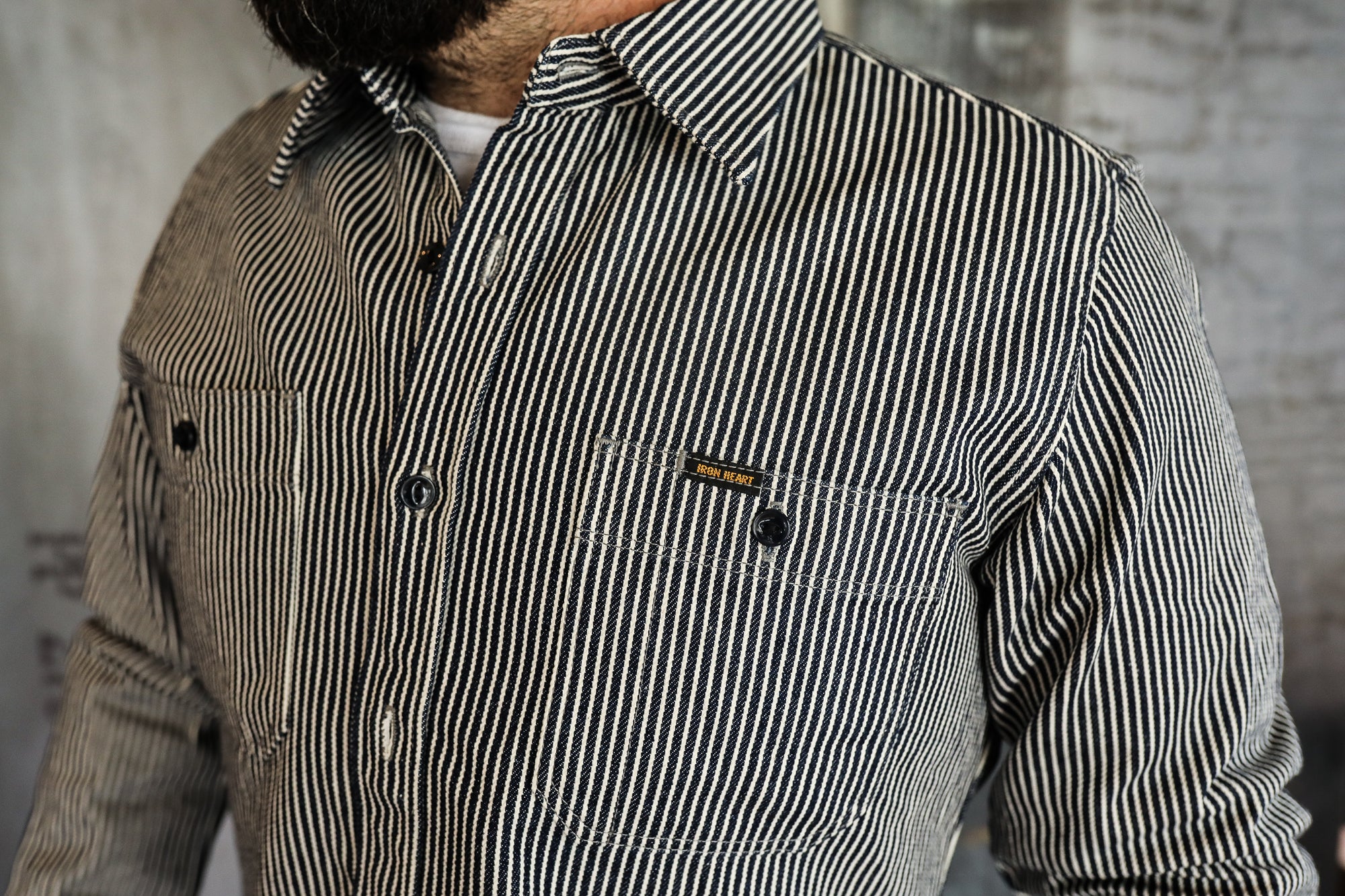 Close-up of a man wearing a black and white striped Iron Heart work shirt with buttoned chest pockets