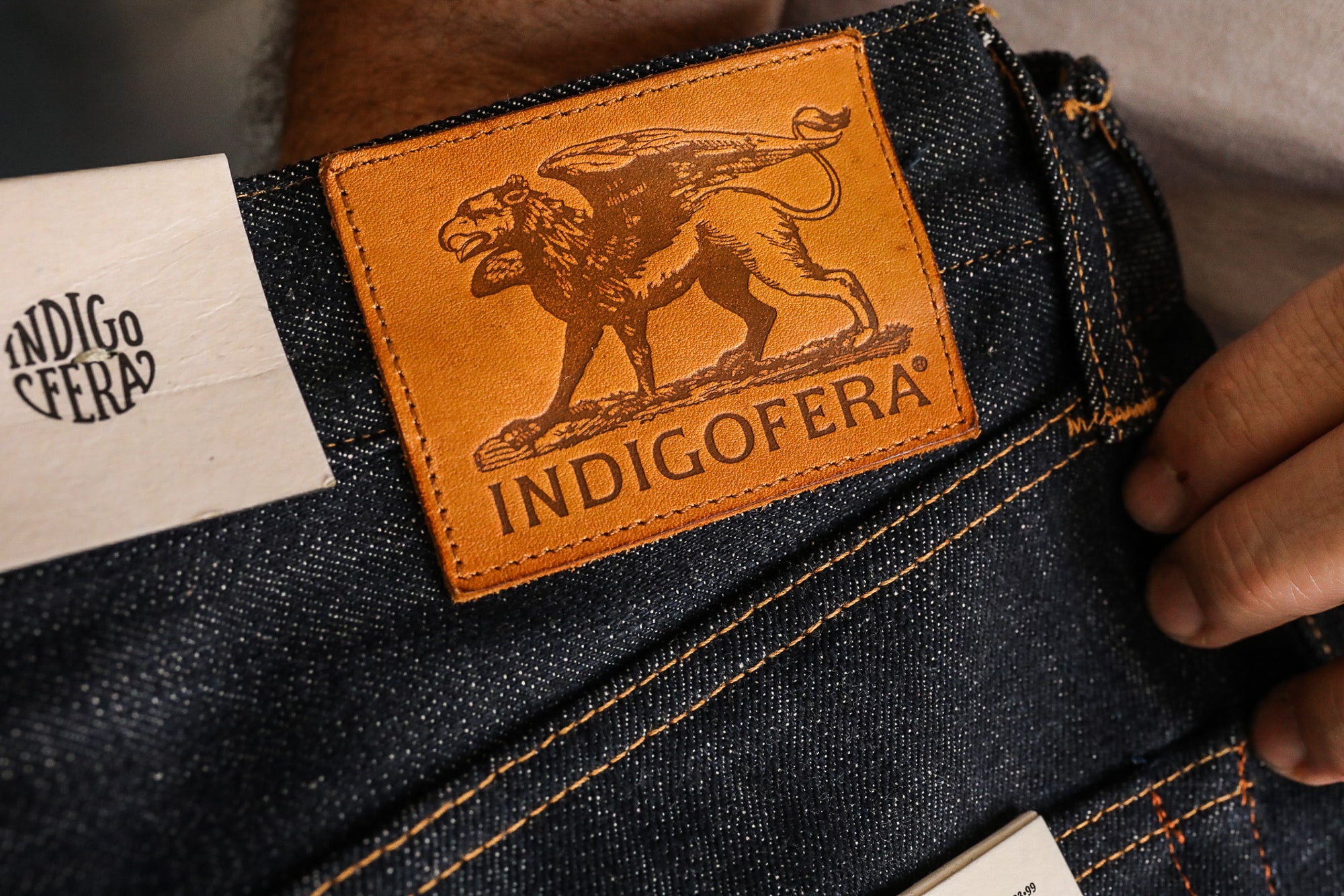 Close-up of Indigofera blue denim jeans with distinctive leather patch and logo label