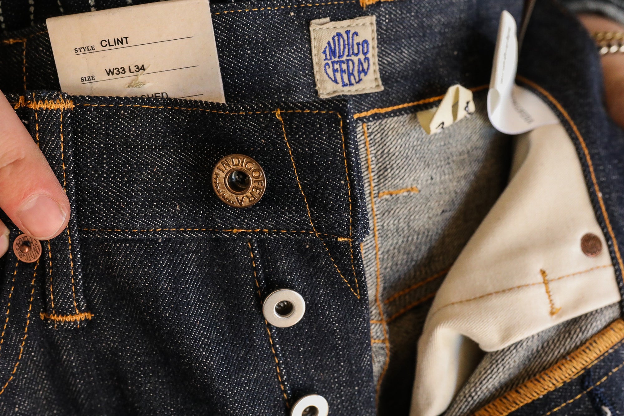 Close-up of Indigofera Clint style raw denim jeans with button fly and W33 L34 size tag