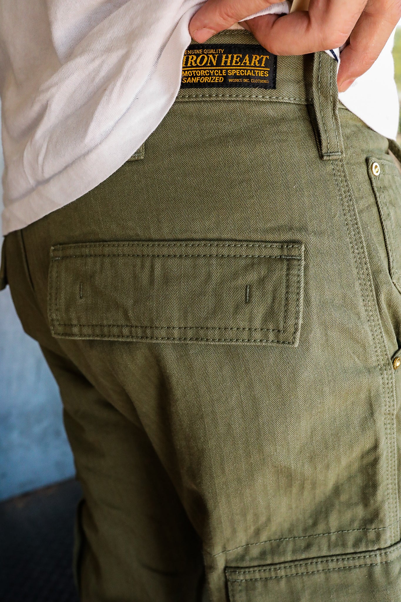 Close-up of person wearing olive green Iron Heart motorcycle specialty pants with detailed stitching and label