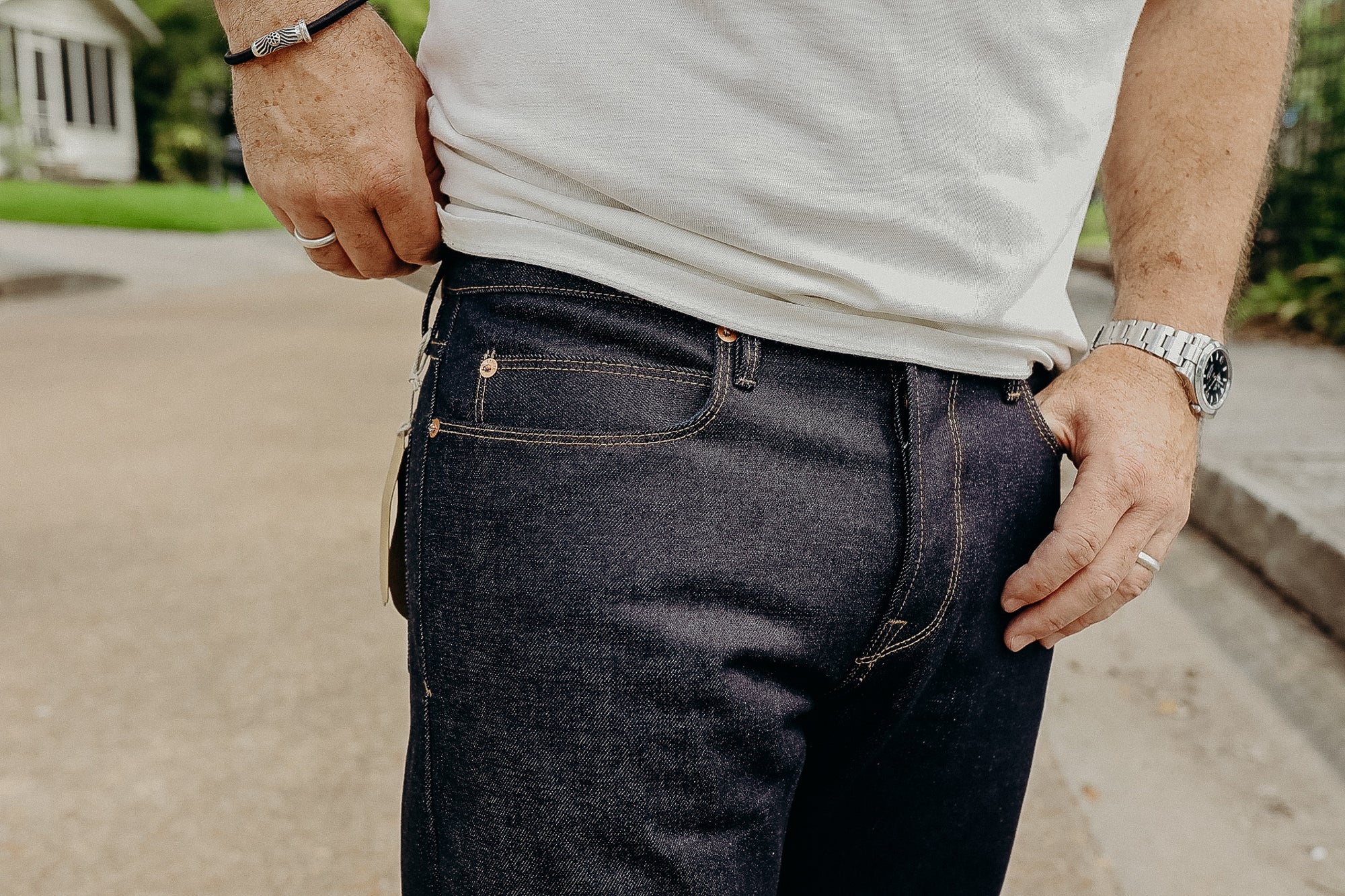 Close-up of man wearing dark denim jeans and white t-shirt, outdoor street background