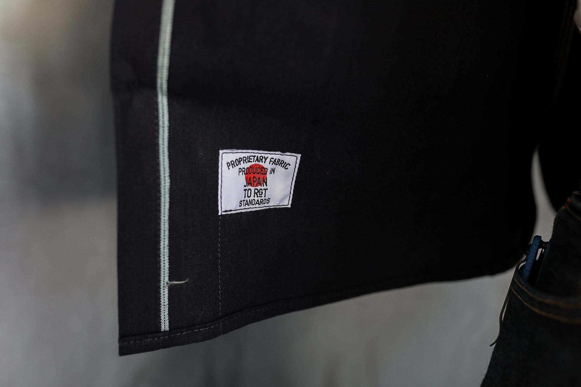 Close-up of black denim fabric with white stitched label reading produced in Japan to RGT standards