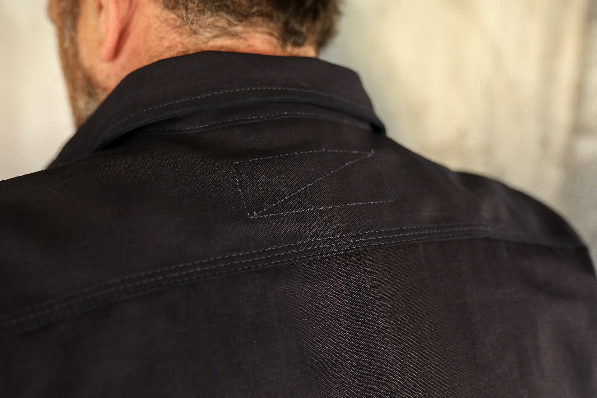 Close-up of back collar and shoulder of black workwear jacket with double stitching detail