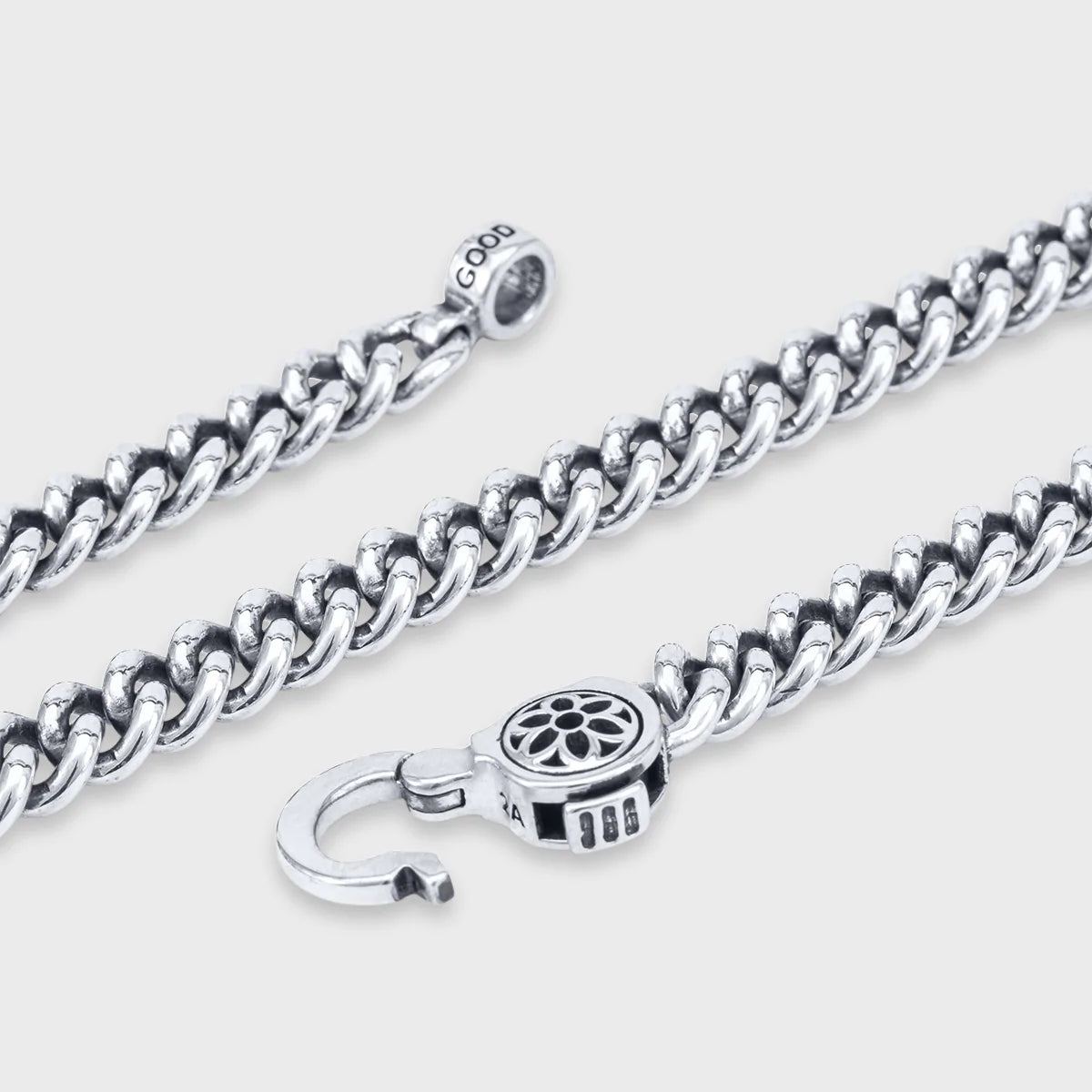 Sterling silver curb chain necklace with detailed floral clasp and GOOD engraved tag on white background