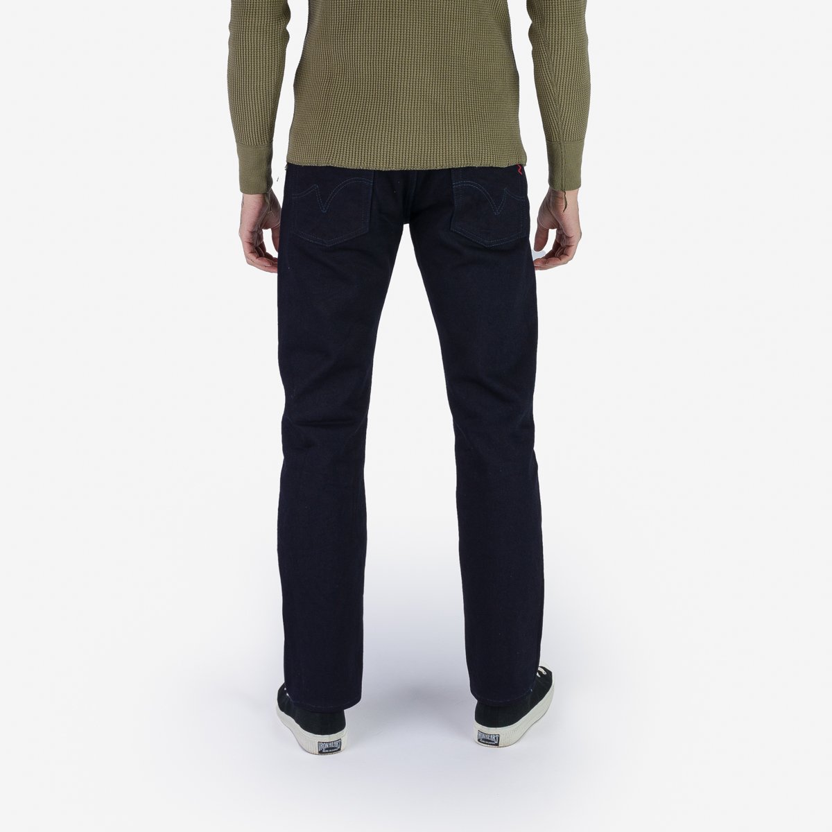 Back view of a person wearing dark blue straight-leg denim jeans with visible back pockets and stitching detail