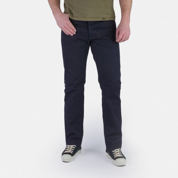 Man wearing slim fit dark navy jeans with casual sneakers on white background