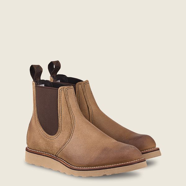Pair of brown leather Chelsea boots with elastic side panels and pull tabs on neutral background